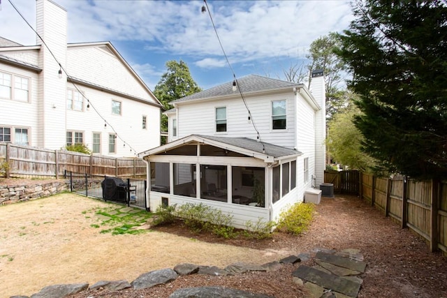 rear view of property with a chimney, a gate, a sunroom, and a fenced backyard