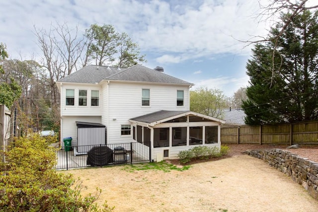 back of house featuring a sunroom, a fenced backyard, and a chimney