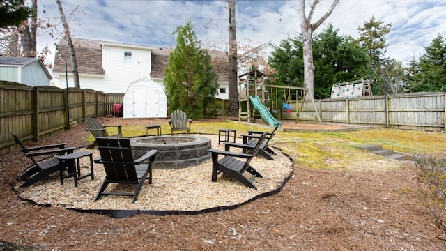 view of yard featuring an outbuilding, a fenced backyard, a fire pit, and a storage unit