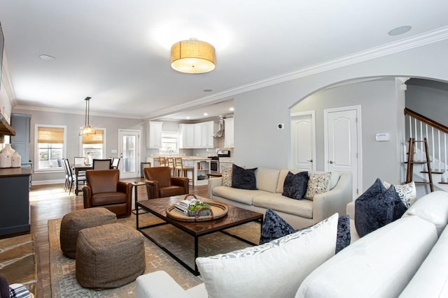 living area with baseboards, arched walkways, stairway, ornamental molding, and wood finished floors