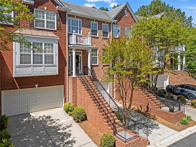 multi unit property with driveway, a garage, stairway, and brick siding