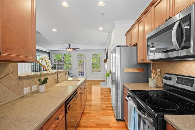 kitchen with light wood-style flooring, a sink, a ceiling fan, and appliances with stainless steel finishes