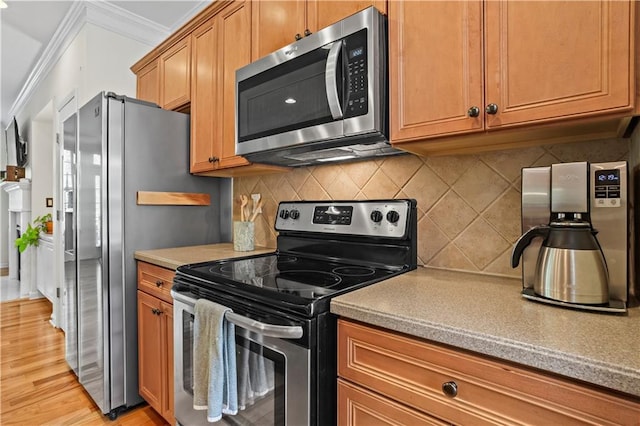 kitchen featuring tasteful backsplash, ornamental molding, light countertops, appliances with stainless steel finishes, and light wood finished floors
