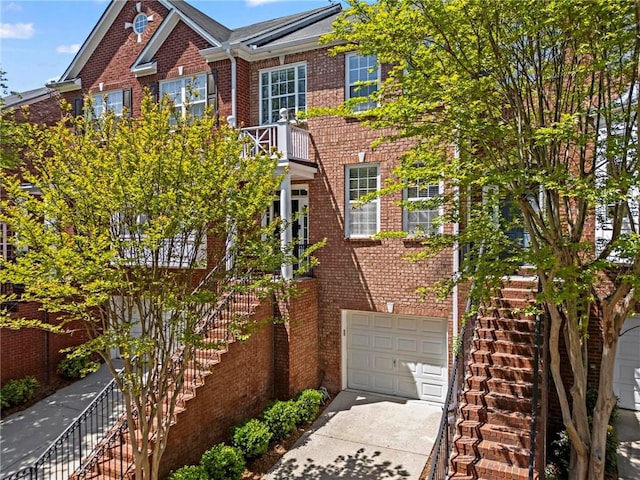 multi unit property featuring brick siding, an attached garage, concrete driveway, and stairs
