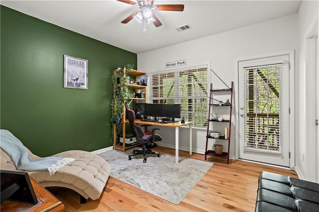 office area with visible vents, baseboards, wood finished floors, and ceiling fan
