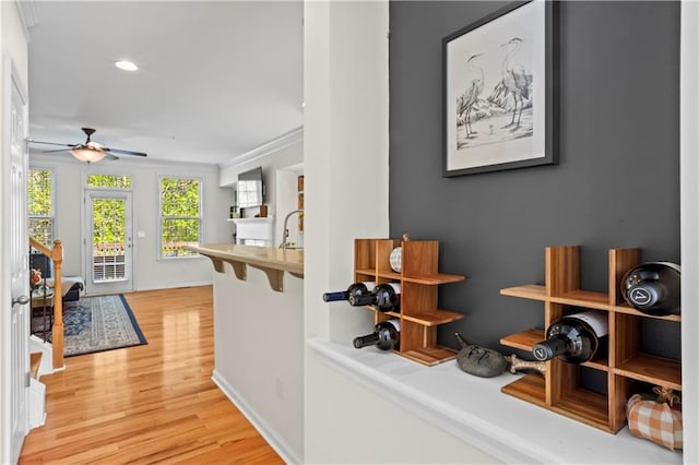 hall featuring recessed lighting, light wood-style floors, baseboards, and crown molding