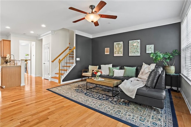 living area featuring baseboards, light wood-type flooring, ornamental molding, recessed lighting, and a ceiling fan