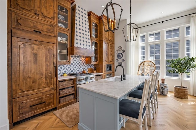 11277 Serenbe Ln, Chattahoochee Hills, GA 30268 - kitchen with stainless steel range, a sink, light stone countertops, a chandelier, and a breakfast bar area