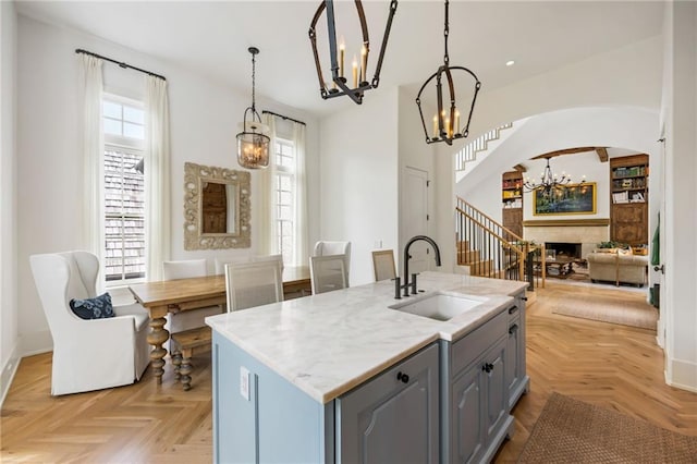 11277 Serenbe Ln, Chattahoochee Hills, GA 30268 - kitchen with a chandelier, a sink, gray cabinets, arched walkways, and a fireplace