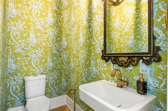 11277 Serenbe Ln, Chattahoochee Hills, GA 30268 - half bathroom with a sink, wallpapered walls, baseboards, toilet, and wood finished floors