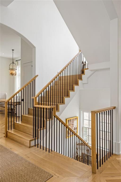 11277 Serenbe Ln, Chattahoochee Hills, GA 30268 - stairs with a chandelier, arched walkways, and a towering ceiling