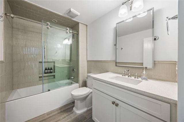11277 Serenbe Ln, Chattahoochee Hills, GA 30268 - bathroom with vanity, combined bath / shower with glass door, toilet, wood tiled floors, and wainscoting