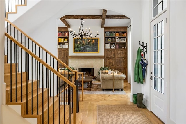11277 Serenbe Ln, Chattahoochee Hills, GA 30268 - foyer entrance featuring arched walkways, a chandelier, stairway, a premium fireplace, and beamed ceiling