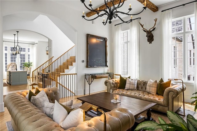 11277 Serenbe Ln, Chattahoochee Hills, GA 30268 - living room featuring a chandelier, arched walkways, wood finished floors, and stairs