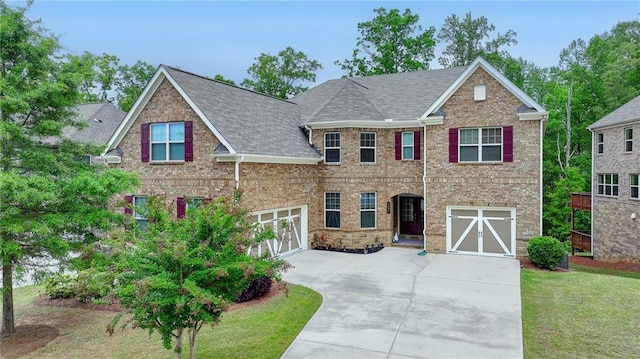 view of front of property with roof with shingles, an attached garage, a front lawn, brick siding, and concrete driveway