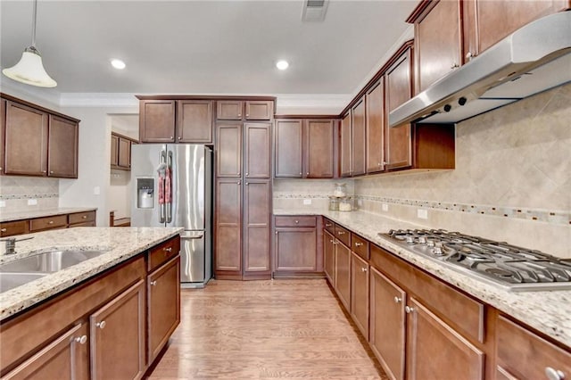 kitchen with decorative backsplash, light wood-type flooring, under cabinet range hood, decorative light fixtures, and stainless steel appliances