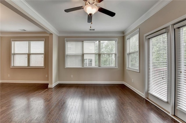 empty room with crown molding, ceiling fan, baseboards, dark wood-type flooring, and visible vents