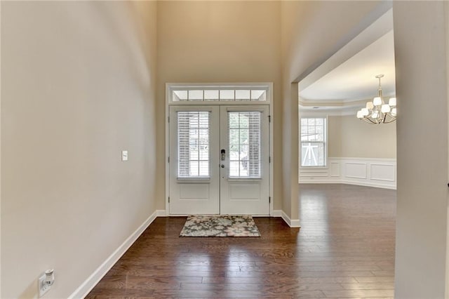 entryway with crown molding, wainscoting, a chandelier, french doors, and dark wood-style floors