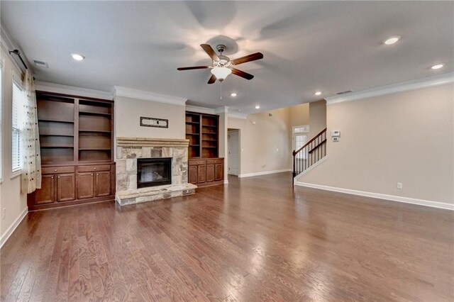 unfurnished living room with baseboards, ceiling fan, ornamental molding, and a stone fireplace