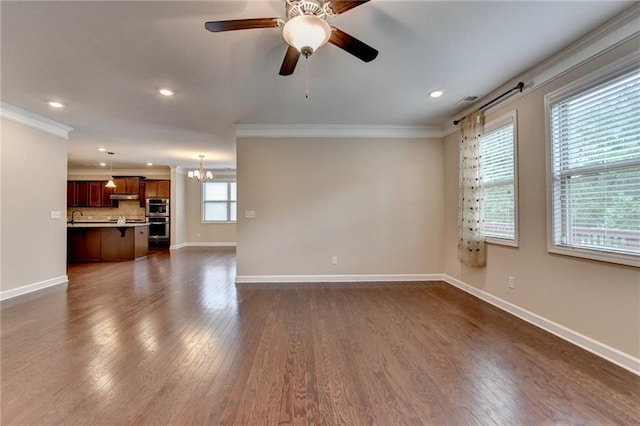 unfurnished living room with crown molding, baseboards, recessed lighting, and dark wood finished floors