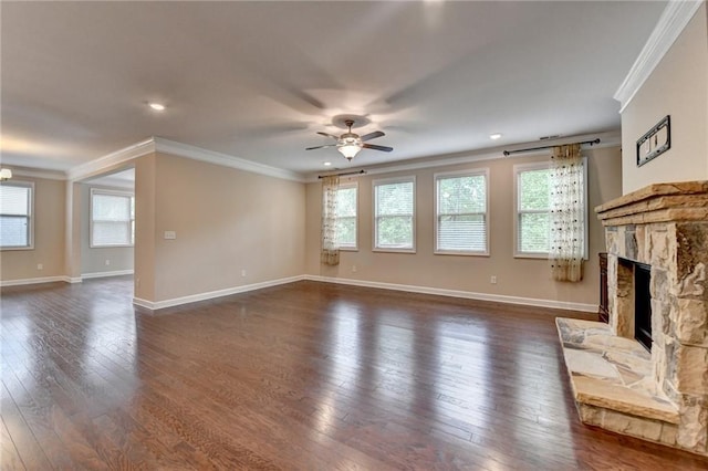 unfurnished living room featuring plenty of natural light, ornamental molding, ceiling fan, and a stone fireplace