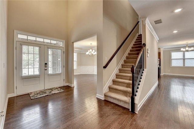 foyer featuring an inviting chandelier, french doors, stairway, and dark wood finished floors