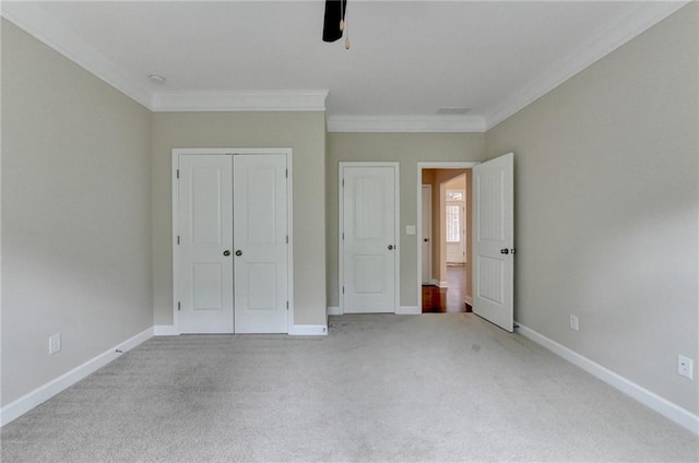 unfurnished bedroom featuring a closet, ornamental molding, carpet, and baseboards