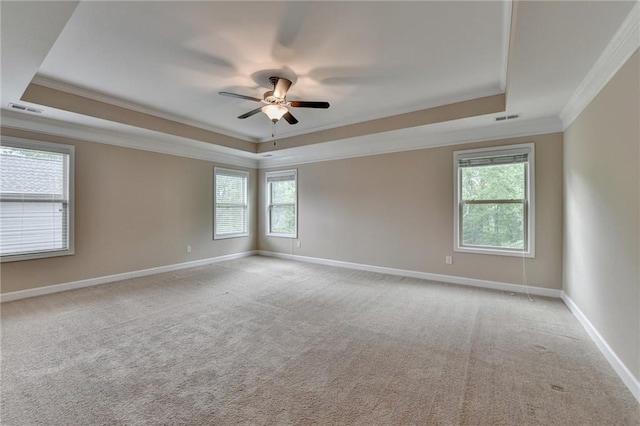 empty room featuring ceiling fan, visible vents, a raised ceiling, baseboards, and ornamental molding