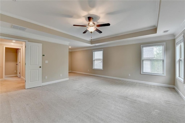 empty room with crown molding, ceiling fan, light carpet, and a tray ceiling