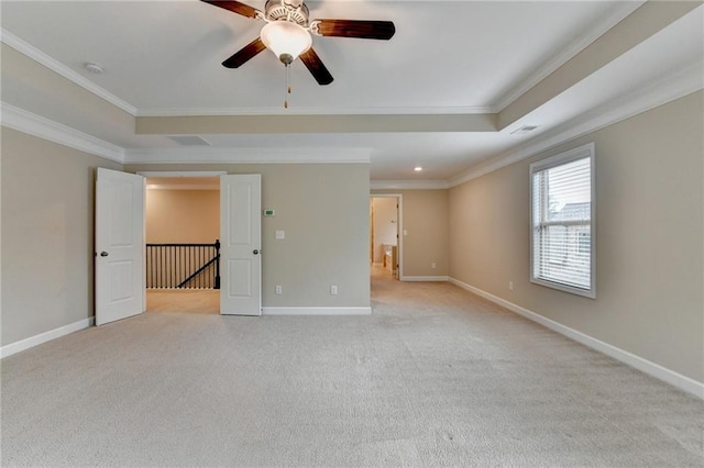 unfurnished room with ornamental molding, light carpet, baseboards, ceiling fan, and a raised ceiling