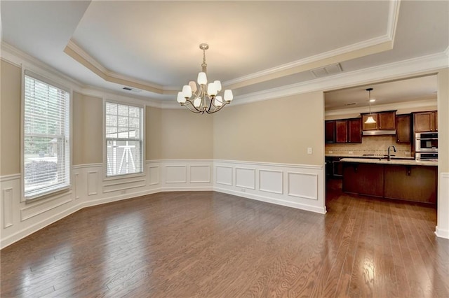 unfurnished dining area featuring visible vents, dark wood finished floors, a notable chandelier, and a tray ceiling