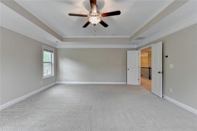 spare room featuring a raised ceiling, ornamental molding, light carpet, and ceiling fan