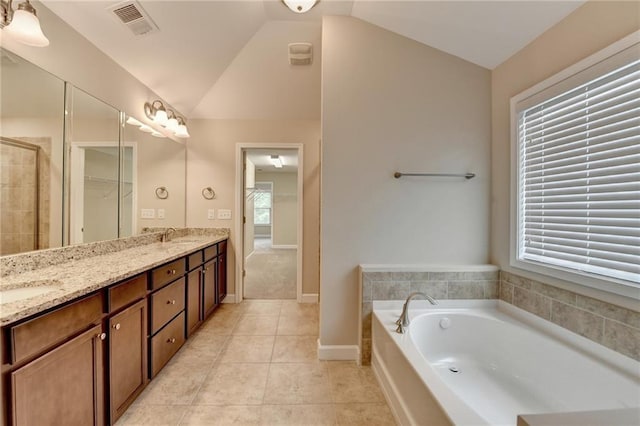 bathroom with tile patterned flooring, a garden tub, vaulted ceiling, and a wealth of natural light