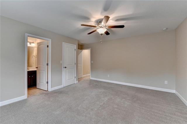 unfurnished bedroom featuring light colored carpet, connected bathroom, baseboards, and ceiling fan