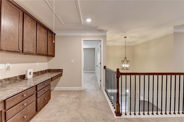 kitchen with dark countertops, light colored carpet, hanging light fixtures, baseboards, and ornamental molding