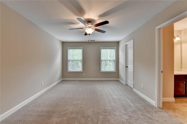 spare room with baseboards, ceiling fan, visible vents, and light colored carpet