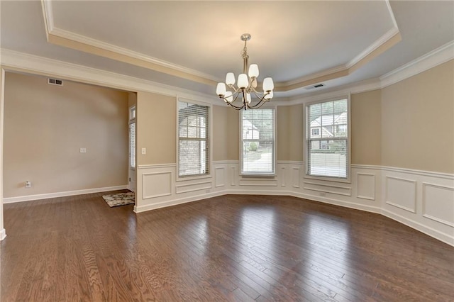 empty room with a raised ceiling, dark wood finished floors, a chandelier, and visible vents