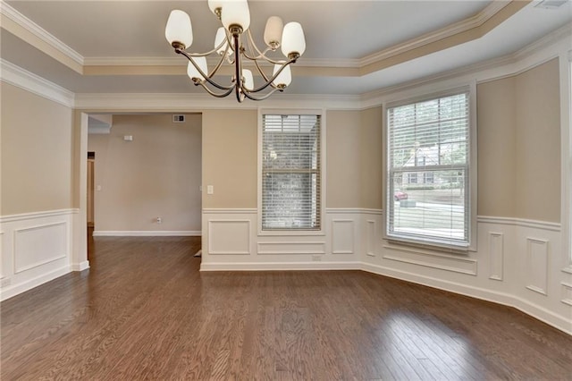 unfurnished room featuring a notable chandelier, wood finished floors, a raised ceiling, and a wainscoted wall