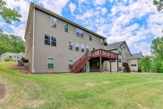 rear view of property with a lawn, a wooden deck, an attached garage, and stairway