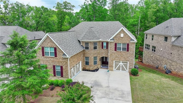 view of front of home with a front yard, brick siding, concrete driveway, an attached garage, and a shingled roof