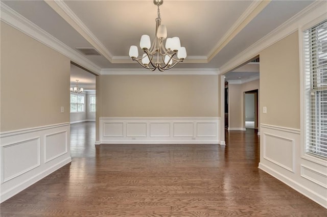 spare room with a notable chandelier, wainscoting, ornamental molding, visible vents, and dark wood-style floors