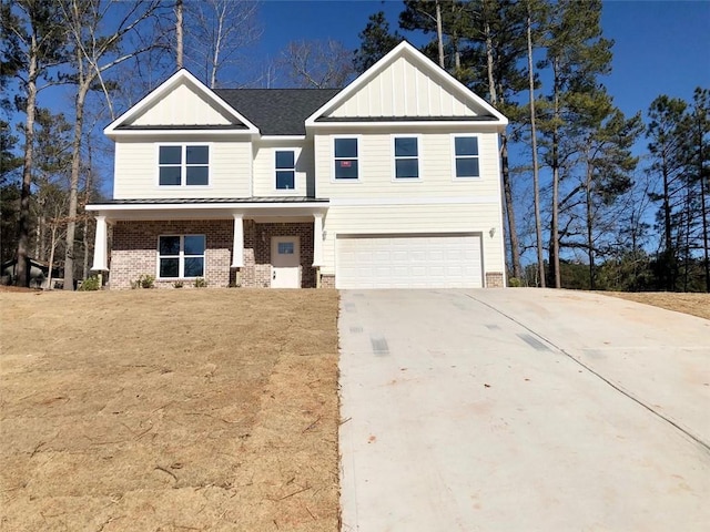 view of front of house featuring a garage, concrete driveway, a standing seam roof, board and batten siding, and brick siding