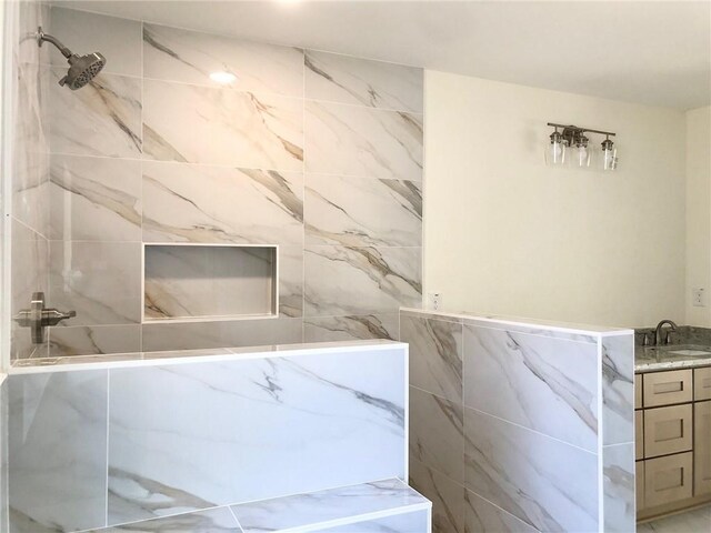 bathroom featuring tile walls, vanity, and a marble finish shower