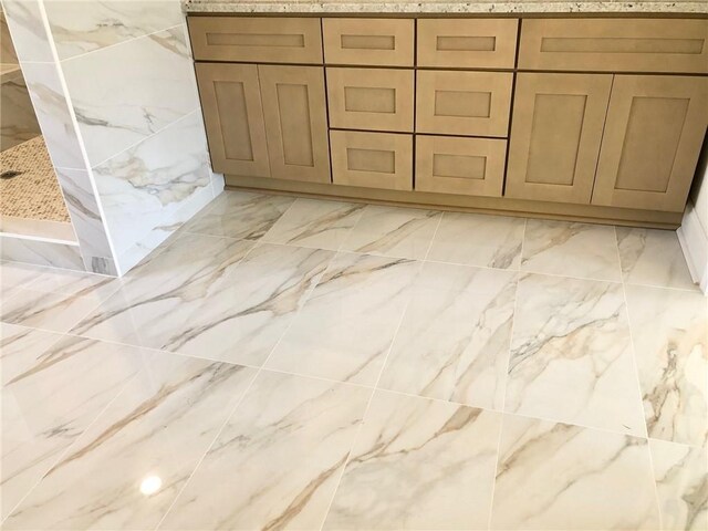 full bathroom featuring marble finish floor and a tile shower