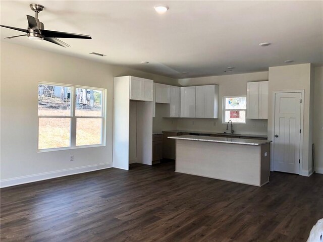 kitchen featuring white cabinetry, open floor plan, range, a center island, and dark countertops