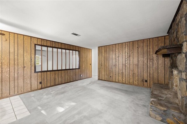 unfurnished living room with carpet, wooden walls, and a fireplace