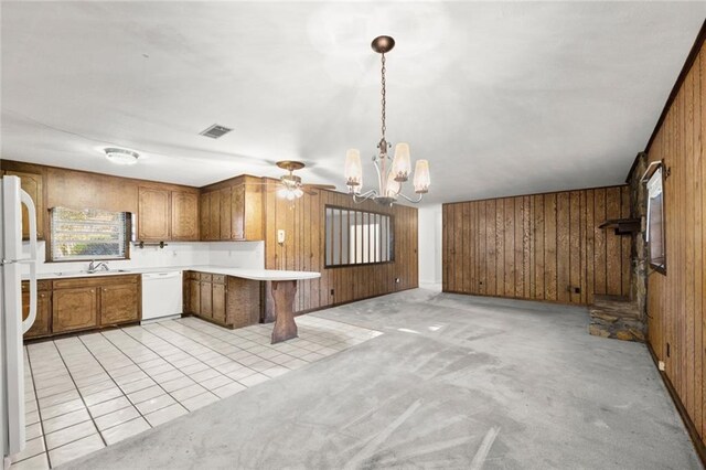 kitchen featuring decorative light fixtures, wood walls, sink, white appliances, and light colored carpet