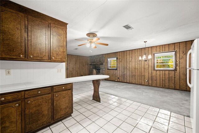 kitchen with wood walls, white refrigerator, decorative light fixtures, and light colored carpet