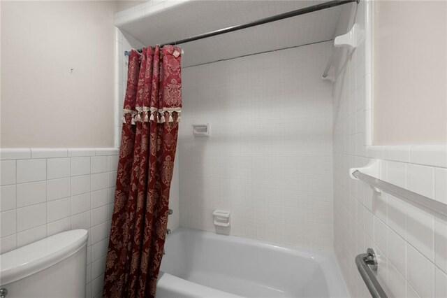 bathroom with shower / bath combo, tile walls, and toilet