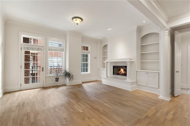 unfurnished living room featuring built in shelves, ornamental molding, light hardwood / wood-style floors, and decorative columns